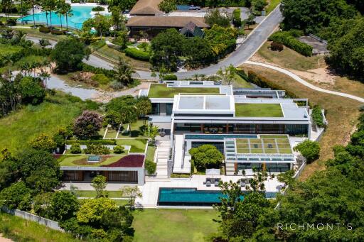 Aerial view of a modern luxury property with multiple swimming pools and greenery.