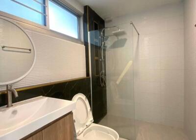 Modern bathroom with round mirror, sink, toilet, and glass shower area