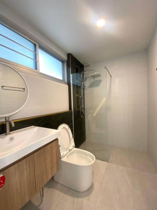 Modern bathroom with round mirror, sink, toilet, and glass shower area