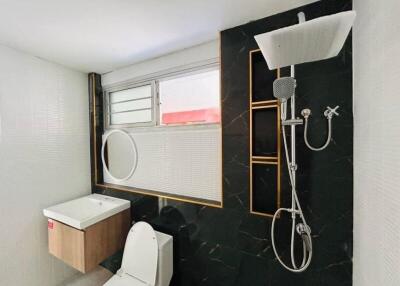 Modern bathroom with black accent wall and large showerhead