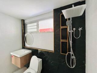 Modern bathroom with black accent wall and large showerhead