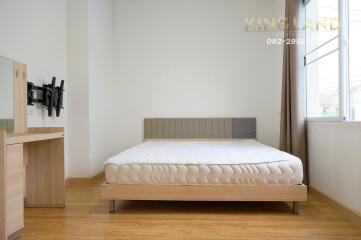 Modern bedroom with a bed, wall-mounted TV bracket, and wooden nightstand