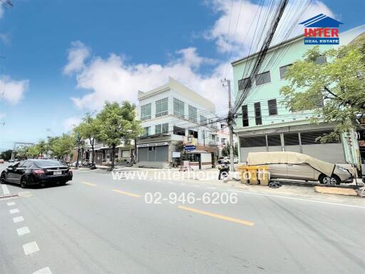 Street view featuring buildings and cars, with a real estate advertisement