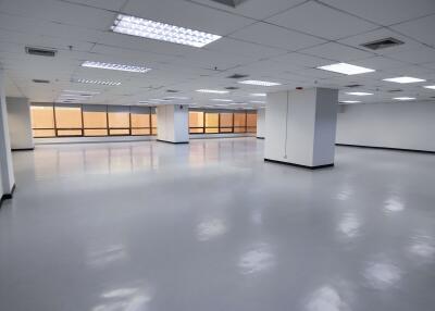 Large empty office space with tiled ceiling and fluorescent lights