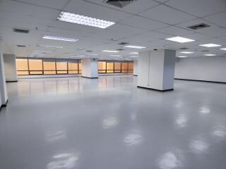 Large empty office space with tiled ceiling and fluorescent lights