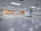 Large empty office space with tiled ceiling and fluorescent lights