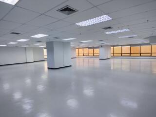 Spacious empty office with large windows and overhead lighting