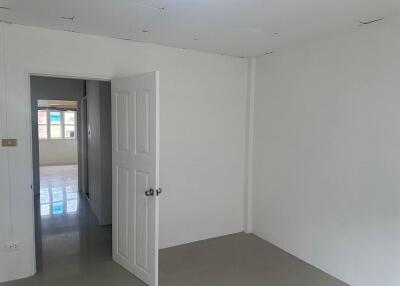 Empty bedroom with an open door leading to another room