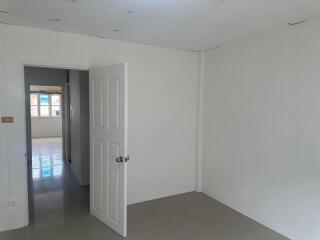 Empty bedroom with an open door leading to another room