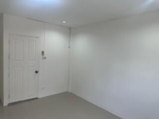 Empty room with white walls, door, and minimal lighting