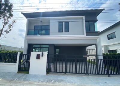 Front view of a modern two-story house with a fenced yard and driveway