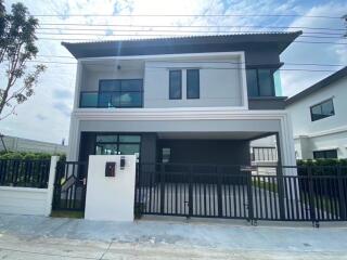 Front view of a modern two-story house with a fenced yard and driveway