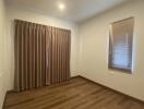 Empty bedroom with wooden floor and curtains