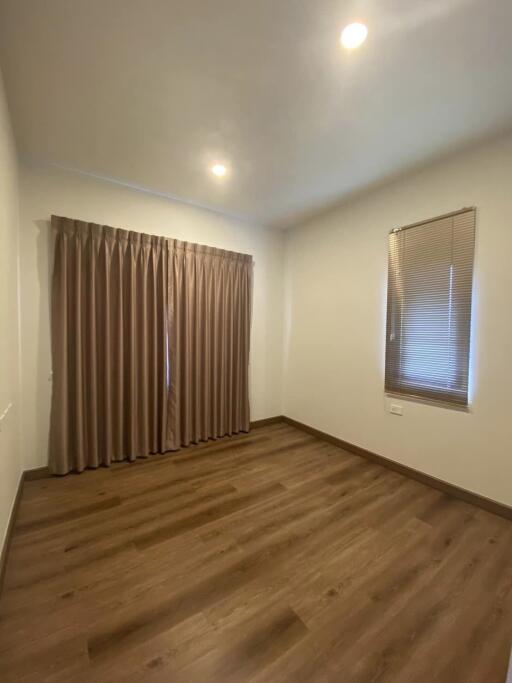 Empty bedroom with wooden floor and curtains