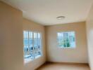 Bright empty bedroom with windows and wooden flooring