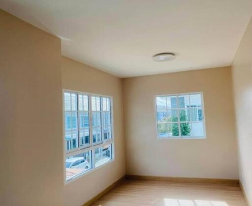 Bright empty bedroom with windows and wooden flooring