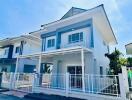 Two-story modern house with white fence and carport