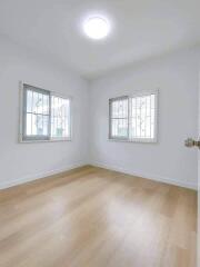 Bright bedroom with wooden flooring and windows