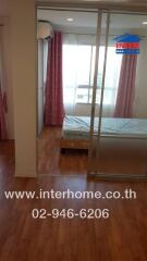 Bedroom with wooden flooring, large window, and pink curtains