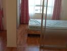 Bedroom with wooden flooring, large window, and pink curtains