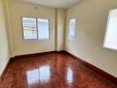 Empty bedroom with wooden floors and two windows