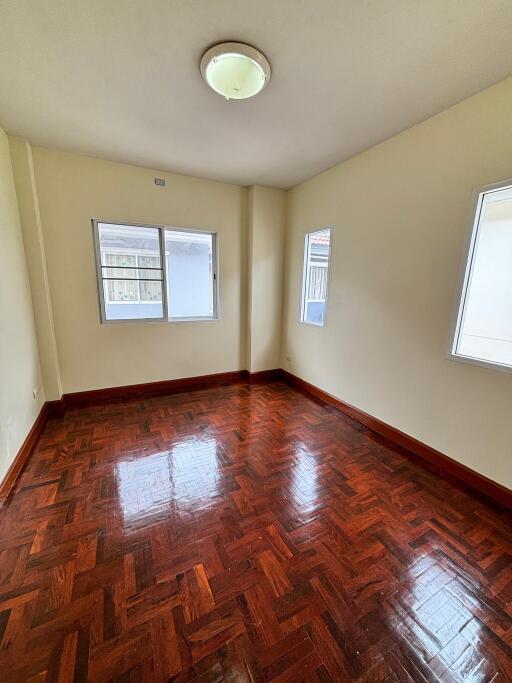 Empty bedroom with wooden floors and two windows