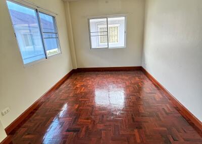 Empty bedroom with wooden floor and two windows