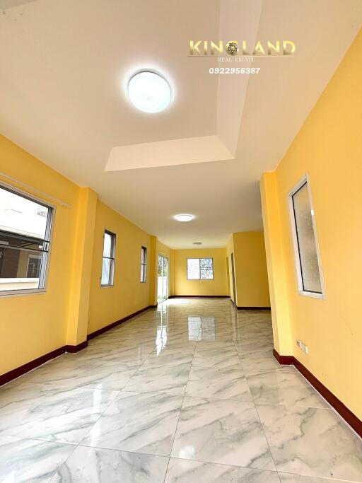 Spacious and bright hallway with yellow walls and large windows