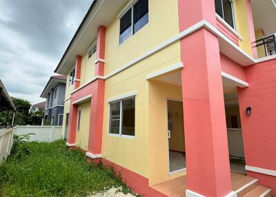 Exterior view of a two-story house with yellow and pink walls