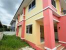 Exterior view of a two-story house with yellow and pink walls