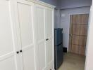 Kitchen area with white cupboards and refrigerator