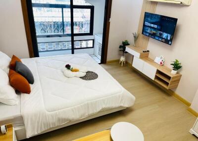 Modern bedroom with a mounted TV, large bed, and balcony view