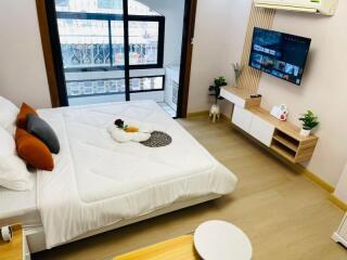 Modern bedroom with a mounted TV, large bed, and balcony view