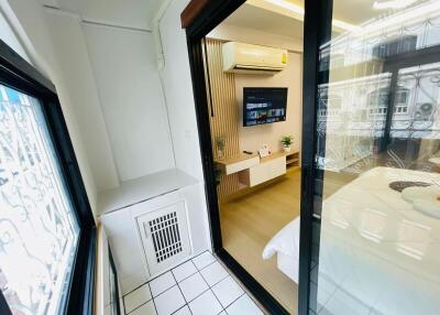 View of a modern bedroom through a glass door from a tiled balcony