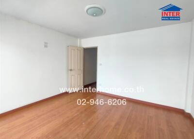 Empty bedroom with wooden flooring and a door