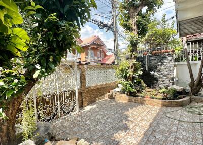 House outdoor area with tiled patio, gate, and greenery