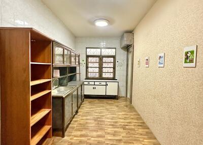 Well-lit kitchen with wooden shelves and large windows.