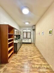 Well-lit kitchen with wooden shelves and large windows.