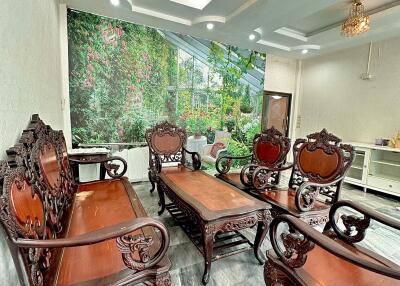 A well-furnished living room with ornate wooden furniture and a large wall mural.