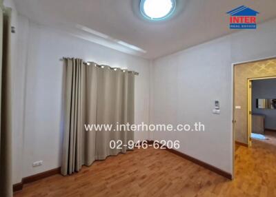 Bedroom with wood flooring, curtained window, and view of another room