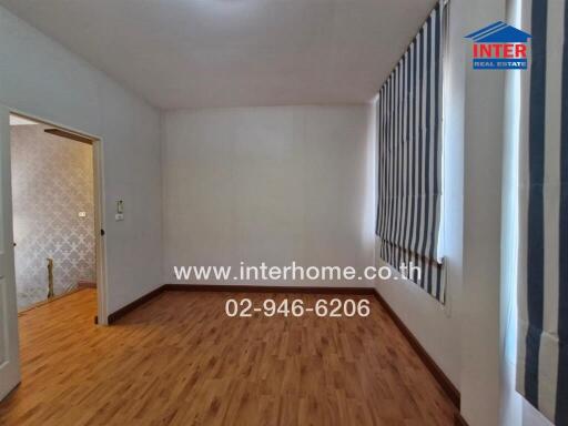 Empty bedroom with wooden flooring and striped curtains