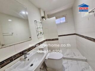 Modern bathroom with tiled floor, sink, toilet, shower area, and a small window.