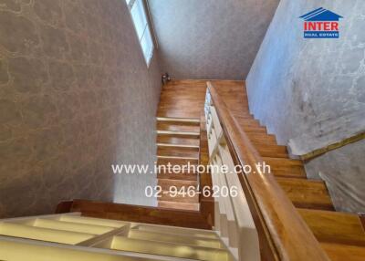 Wooden staircase with patterned wallpaper and a window