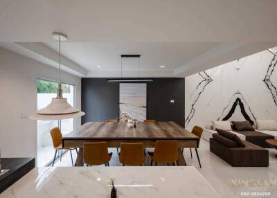 Modern living and dining space with a large wooden table, stylish lighting, and comfortable seating