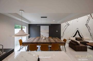 Modern living and dining space with a large wooden table, stylish lighting, and comfortable seating