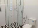 Modern bathroom with a glass shower enclosure and checkered floor tiles