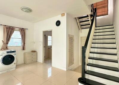 A bright and spacious living area with staircase, washer, and storage.