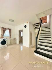 A bright and spacious living area with staircase, washer, and storage.