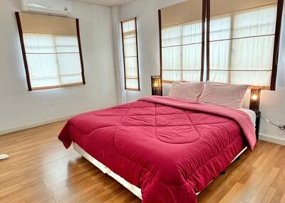 Spacious bedroom with wooden flooring and large windows