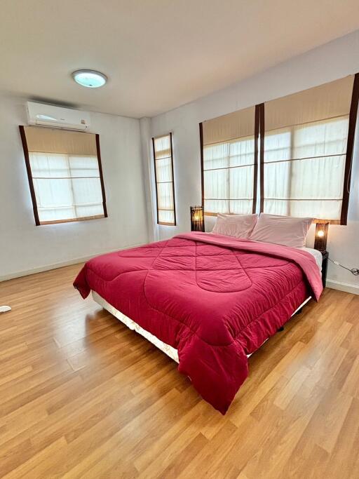 Spacious bedroom with wooden flooring and large windows